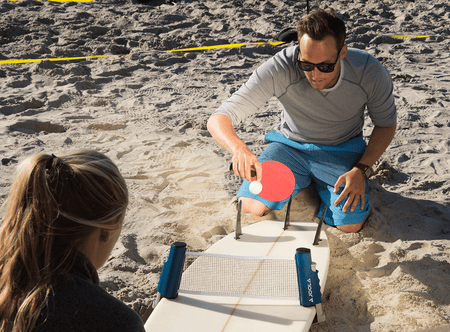 Man and woman playing table tennis outdoors