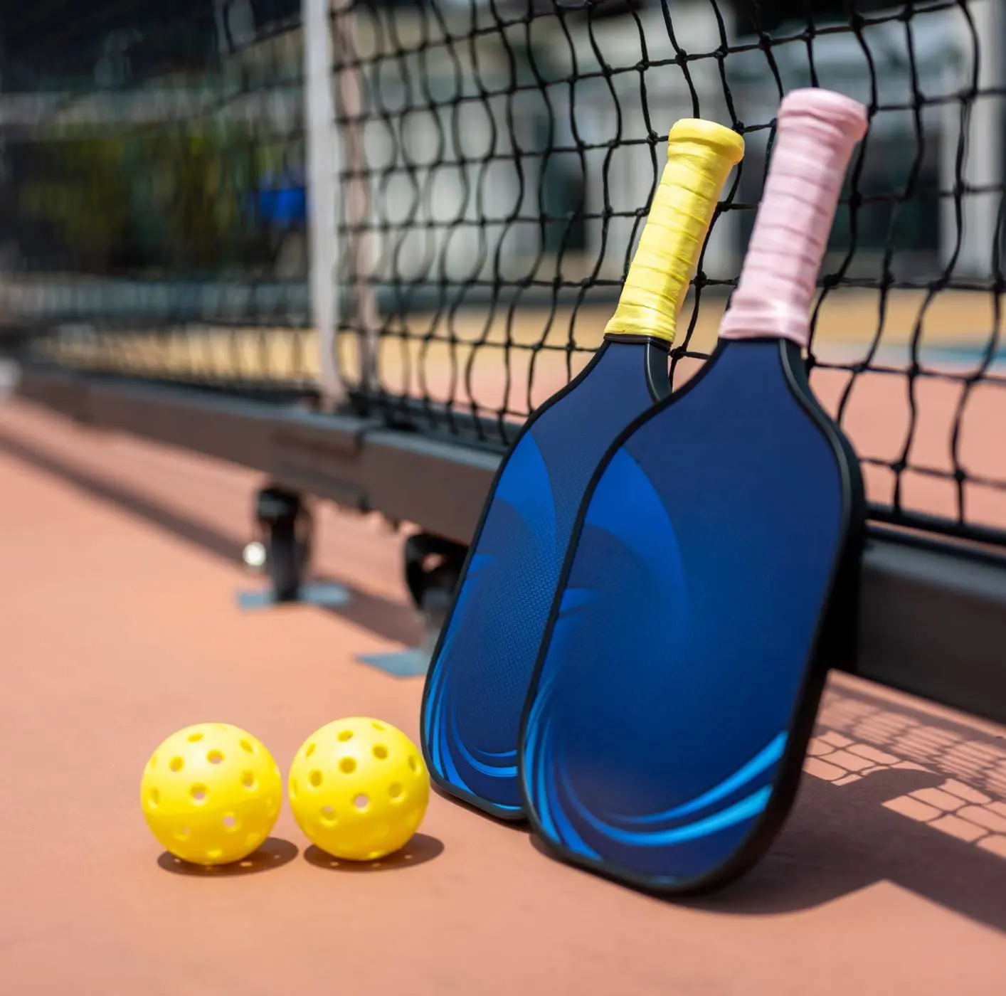 Yellow pickleballs near paddles on court