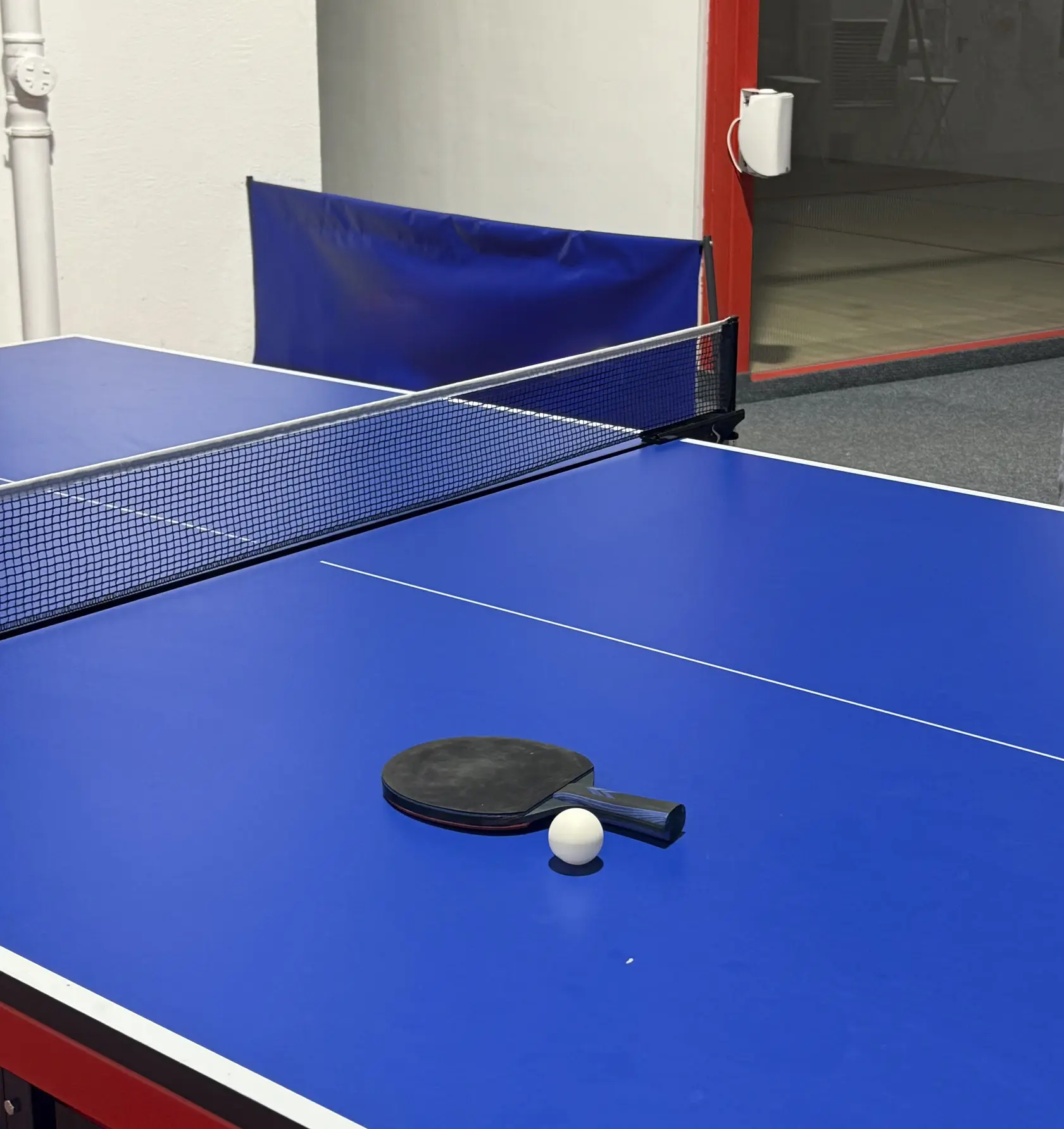 Table tennis equipment set on a blue table in an indoor sports center, prepared for play