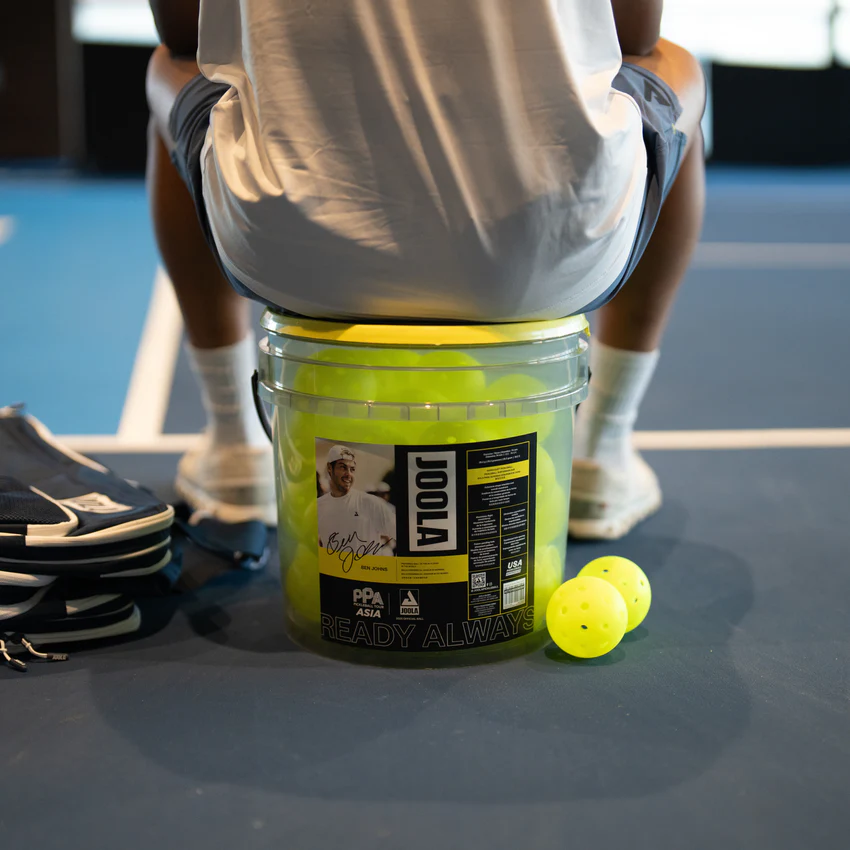 Person sitting on pickleball bucket